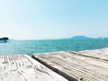 Wooden boardwalk by sea against clear sky