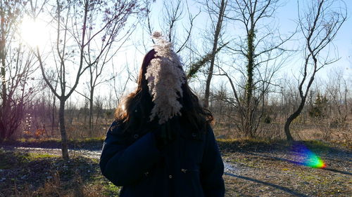 Woman standing by bare trees on field during winter