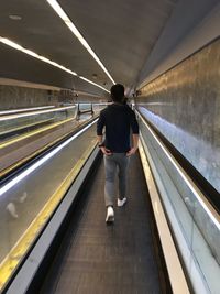 Rear view of man standing on escalator