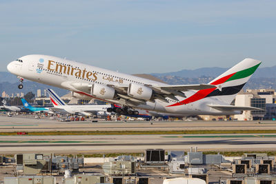 Airplane flying over airport runway against sky