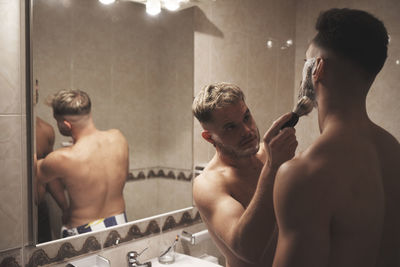 Young man with arms outstretched in bathroom