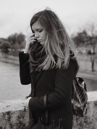 Thoughtful woman standing against lake