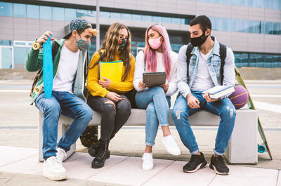 Friends wearing masks studying while sitting on seat