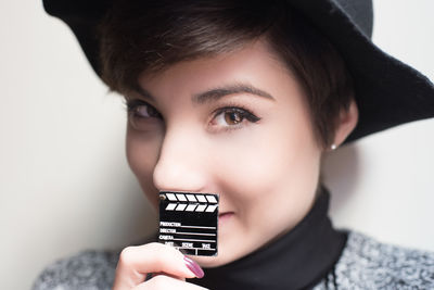 Close-up portrait of young woman holding film slate toy