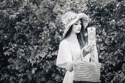 Woman wearing hat standing against plants