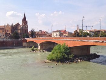 Bridge over river in city against sky