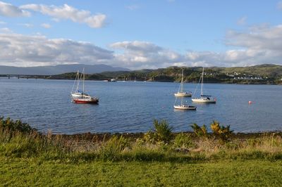 Sailboats moored on sea against sky