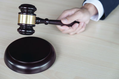 Cropped hand of lawyer holding gavel at desk