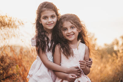 Two little sisters hugging each other during a sunset