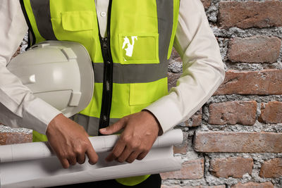 Midsection of man standing on brick wall