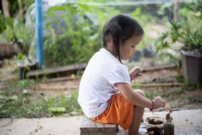 Side view of young woman looking away while standing outdoors