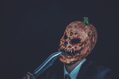 Close-up of man with halloween make-up against black background