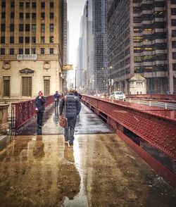 People on wet road in city during winter