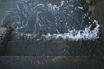 High angle view of sea waves splashing on rocks