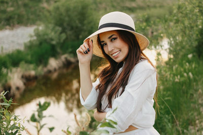 Portrait of beautiful young woman by plants against sky