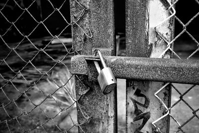 Close-up of closed gate against fence