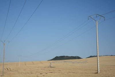 Field of straw and sprinkler against clear blue sky