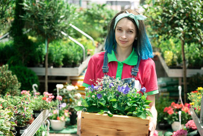 Portrait of young woman standing by plants