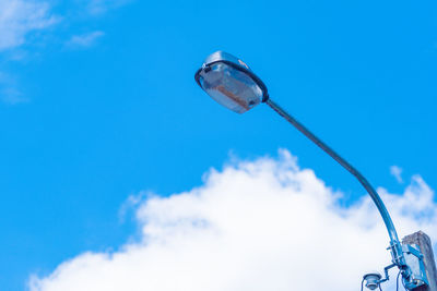 Low angle view of lighting equipment against blue sky