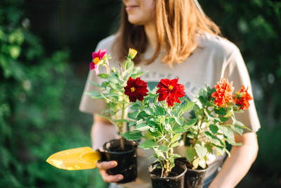 Young woman holding flower pot while working in garden