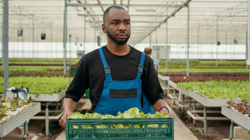 Portrait of young man standing in greenhouse