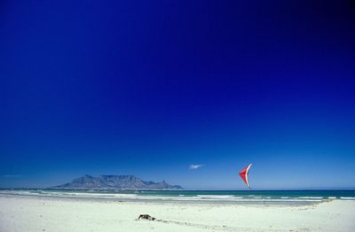 Scenic view of beach against clear blue sky