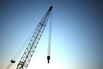 Low angle view of crane against clear blue sky