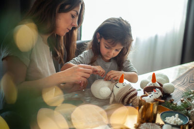 Mother and daughter making christmas decoration while sitting at home
