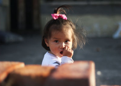 Portrait of cute baby girl sucking thumb outdoors