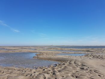 Scenic view of beach against blue sky