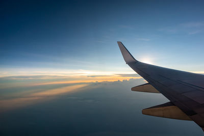 Airplane wing against sky during sunset