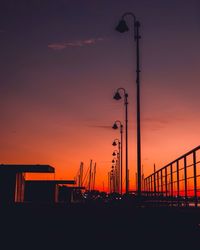 Silhouette street lights against orange sky