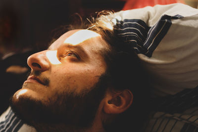 Close-up of thoughtful young man looking away while lying on bed