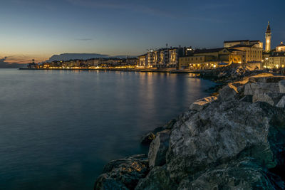 Illuminated buildings by sea at night