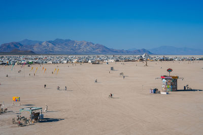 People at beach against clear blue sky