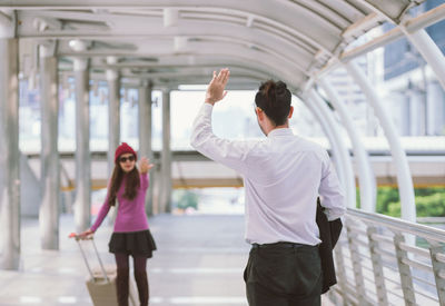 Couple gesturing on elevated walkway at airport