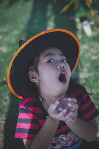 Portrait of girl wearing witch hat holding crystal ball