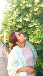 Girl looking away while standing against plants