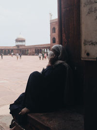 Rear view of woman sitting on bench against clear sky