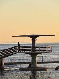 Silhouette pier over sea against clear sky during sunset