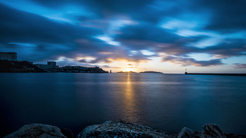 Scenic view of sea by buildings against sky during sunset