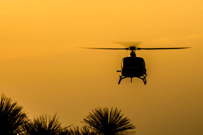 Low angle view of silhouette helicopter against sky during sunset