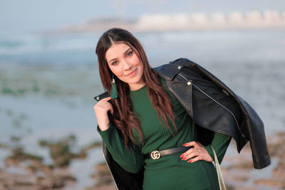 Portrait of mature woman standing against sea