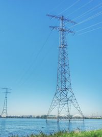 Low angle view of electricity pylon against clear blue sky