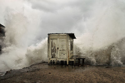 Built structure on shore being hitted by waves on stormy weather