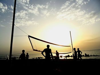 Silhouette people in sea at sunset