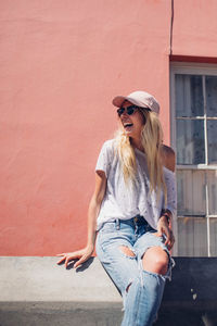 Portrait of smiling young woman standing against wall