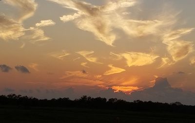 Scenic view of silhouette field against sky at sunset