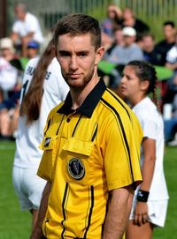 Portrait of young man standing on soccer field