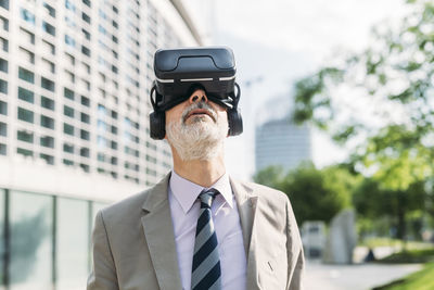 Businessman with virtual reality simulator standing in front of building